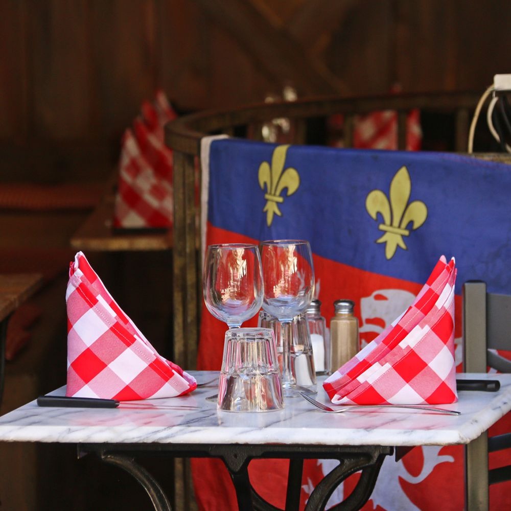 A marble table in a Lyon bouchon set with red checked napkins and wine glasses